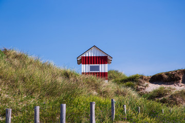 red and white beach cabin on danish seaside