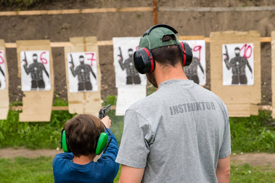 Gun instructor teaching young kid at shooting range