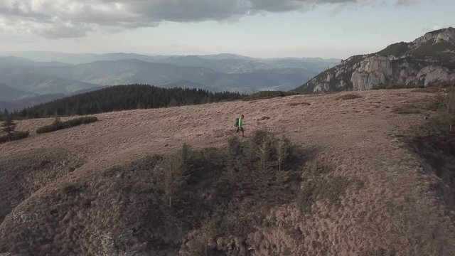 Aerial view. Drone fallows man hiker on top of the mountain. Wilderness exploration. Living to explore concept