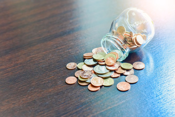 Isolated Glass Jar with Coins Spilling Out 