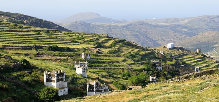 Panoramic spring landscape with famous traditional decorated dovecotes and hedges on the Tinos island and sea in the background, Greece
