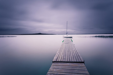 Marine landscape with moored yacht at the quiet bay. Smooth water surface on long exposure shot.