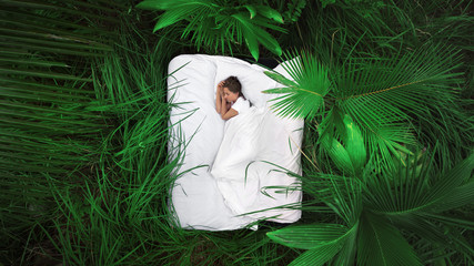 A hidden place. Sleeping woman in deep jungle forest lies on airbed,View from above - obrazy, fototapety, plakaty