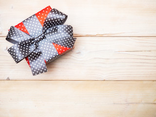 Birthday present with gray satin tape on wooden board. Holidays concept