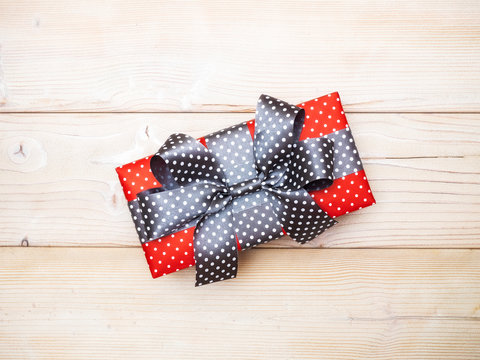 Gift box in glittery paper with bow on wooden board. Holidays concept