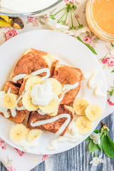 Obraz na płótnie Canvas Cottage cheese pancakes in the form of cubes with banana, yogurt, honey and cherry blossom flowers on grey wooden background. Healthy breakfast food.