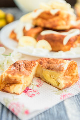 Cottage cheese pancakes in the form of cubes with banana, yogurt, honey and cherry blossom flowers on grey wooden background. Healthy breakfast food.