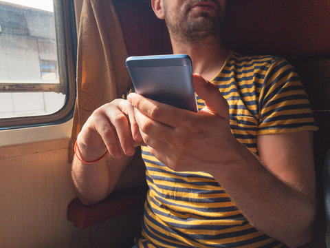 Man using cellphone while traveling in train.