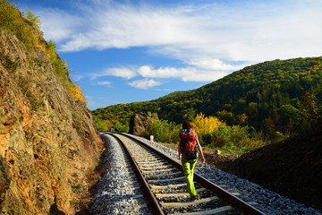 Young girl with backpack walking on railway track in autumn, Czech republic
