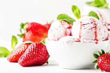 Strawberry ice cream with jam topping, decorated with green mint leaves, gray background, selective focus
