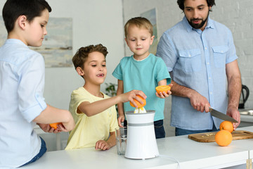family making fresh orange juice together in kitchen at home