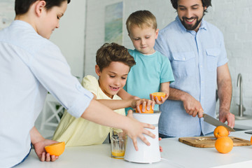 happy family making fresh orange juice in kitchen at home