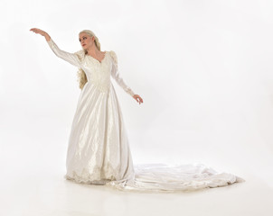 Naklejka premium full length portrait of blonde woman wearing long white bridal gown. standing pose on white studio background.