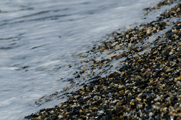 pebble beach washed by sea waves, small and various stones forming the shore
