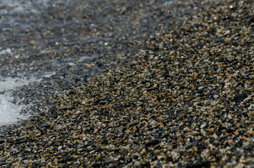 pebble beach washed by sea waves, small and various stones forming the shore