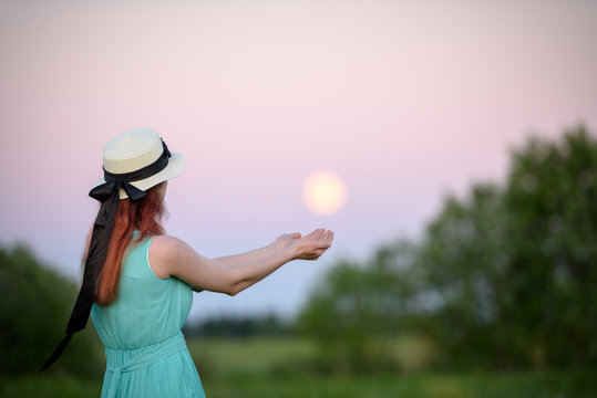 Beautiful girl in the field against the sky with the moon