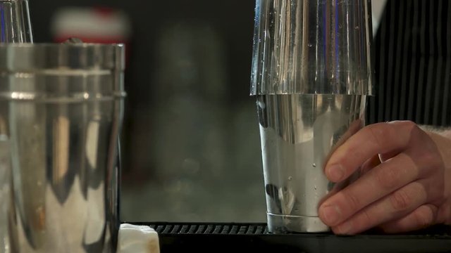 Barman shaking metal shakers, cooking cocktail. Concept of bartender working in night club.