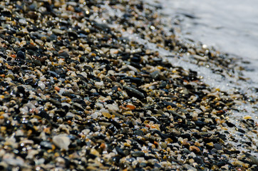 pebble beach washed by sea waves, small and various stones forming the shore