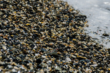 pebble beach washed by sea waves, small and various stones forming the shore