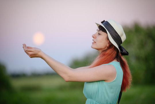 Beautiful girl in the field against the sky with the moon