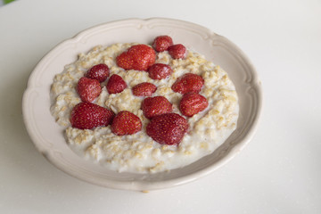 Oatmeal porridge on milk with strawberries. Perfect as a healthy breakfast.
