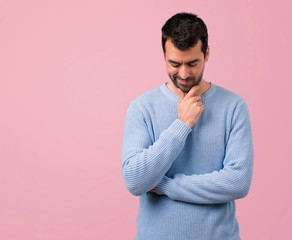 Handsome man standing and looking down on pink background