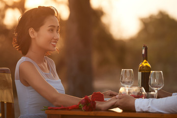 Portrait shot of attractive young woman enjoying romantic date with her loving boyfriend while spending vacation on tropical island, profile view