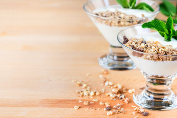 diet healthy Breakfast: white yogurt with granola  decorated with mint leaves in a transparent glass