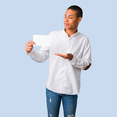Young african american man with white shirt holding an empty white placard for insert a concept on...