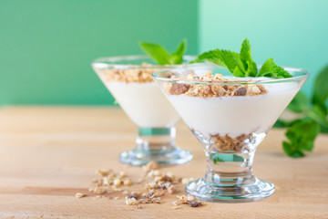 diet healthy Breakfast: white yogurt with granola  decorated with mint leaves in a transparent glass