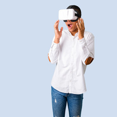 Young african american man with white shirt using VR glasses. Virtual reality experience on isolated blue background