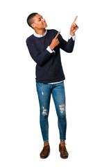 Young african american man pointing with the index finger a great idea and looking up on isolated white background