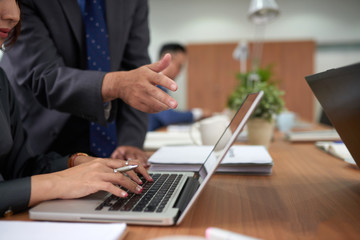 Close-up shot of middle-aged entrepreneur consulting his female subordinate while she  working on ambitious start-up project with help of laptop, interior of open plan office on background