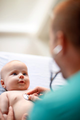 Baby looking at doctor on checkup with stethoscope