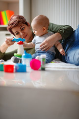 Mother with son playing with toys in children's room