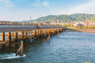 View of Uji city with the Uji Bridge, Uji River, houses, mountain and blue sky