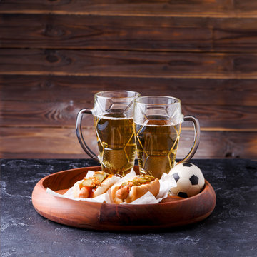 Picture of two mugs of beer and hot dogs on wooden tray
