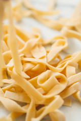 Homemade uncooked egg noodles on a white marble table. The concept of healthy food. Close up.