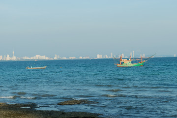 Boat is fishing in front of blur city background