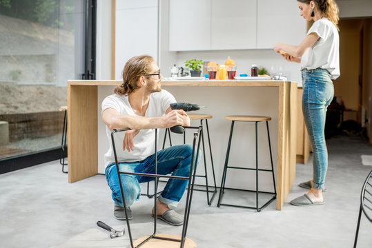 Young couple doing house chores assembling chair and doing order at the kitchen of the modern apartment