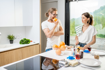 Obraz na płótnie Canvas Young couple cooking breakfast with healthy food and coffee standing at the modern kitchen interior