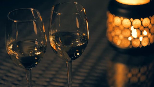 Cinemagraph - Two white wine wineglasses with  lantern with lighted candle on table. Concept of romance. Motion Photo.