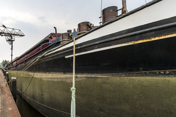 Barco de transporte de mercancía cargando en una fábrica junto al canal