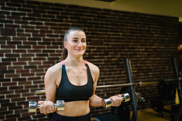 Girl holding the dumbbells in his hands. Portrait of strong sporty woman doing exercise with...