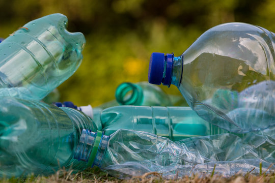 Close up on Empty Plastic bottles in a green nature park background, littering of the environment background.