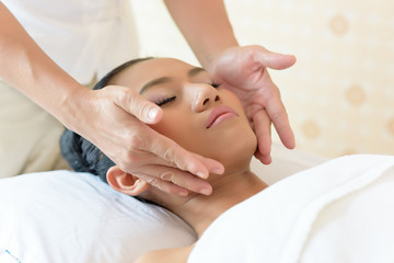 Fototapeta na wymiar Young asian woman enjoying face massage in luxurious beauty salon.