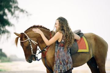 Obraz premium Pretty young lady riding a horse on the beach background of the sea