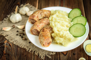 Grilled chicken sausage with mashed potato, cucumber and boiled eggs on wooden background. Healthy lunch or dinner.