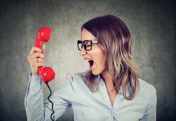 Portrait of a young angry woman yelling at the phone