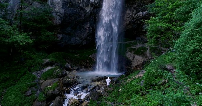 European man with beard is doing waterfall-meditation while standing under big waterfall in austria, wildensteiner waterfall